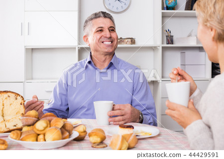 Wife treats husband with tasty pastries at table at home Wife treats husband with tasty pastries at table at home 44429591