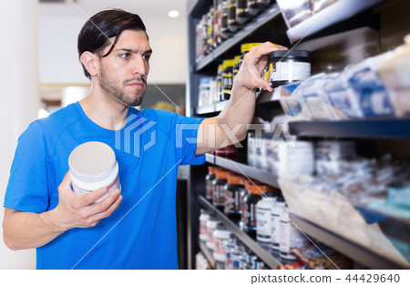 Serious sportman attentively looking sport nutrition products 44429640