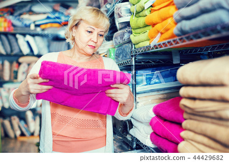 mature woman holding cotton colour towel in the textile shop mature woman holding cotton colour towel in the textile shop 44429682