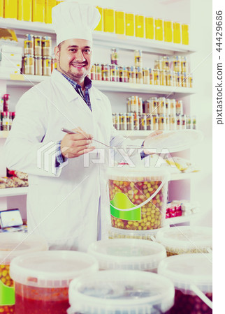 Shop staff standing near containers with olives in flavoured brine Shop staff standing near containers with olives in flavoured brine 44429686