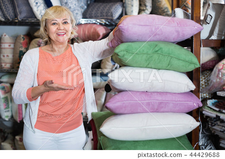 Adult female buyer choosing colour pillows in the textile store Adult female buyer choosing colour pillows in the textile store 44429688