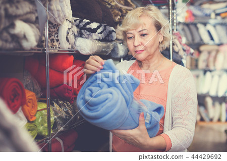 Adult female buyer choosing colour plaids in the textile store Adult female buyer choosing colour plaids in the textile store 44429692
