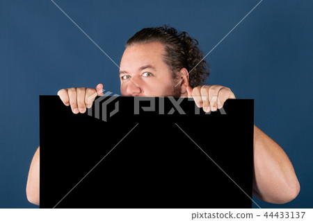 Funny fat man in a bright striped shirt holding a black writing board Funny fat man in a bright striped shirt holding a black writing board 44433137