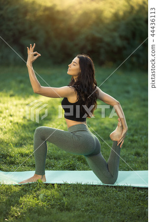 Woman practicing yoga outdoors in park 44436113