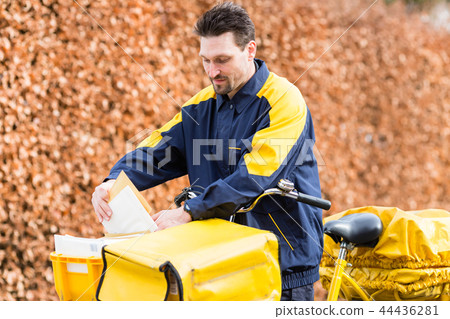 Postman riding his cargo bike carrying out mail in neighborhood 44436281