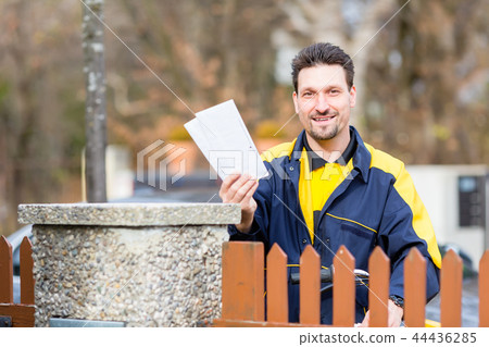 Postman delivering letters to mailbox of recipient 44436285