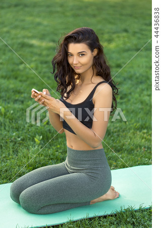 Fitness girl with a smartphone on nature background 44436838