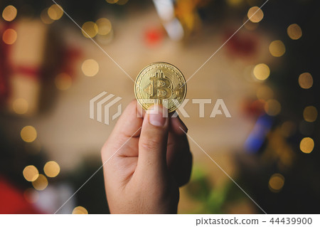 Hand Holding Bitcoin Above Christmas Decoration 44439900