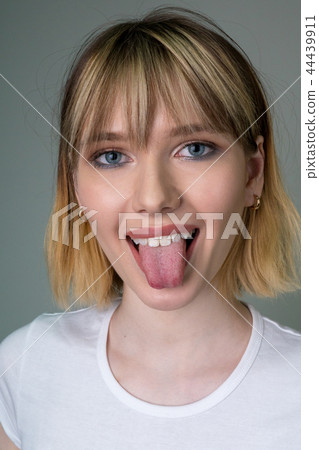 Portrait of a beautiful girl showing the tongue. 44439911