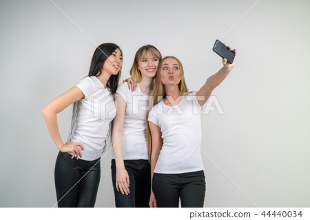 Beautiful funny girls make selfie. Girls in white T-shirts. 44440034