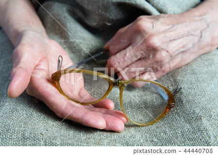 Broken glasses in the hands of an old woman. Broken glasses in the hands of an old woman. 44440708