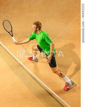 The one jumping player, caucasian fit man, playing tennis on the earthen court The one jumping player, caucasian fit man, playing tennis on the earthen court 44441553