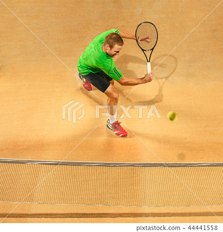 The one jumping player, caucasian fit man, playing tennis on the earthen court 44441558