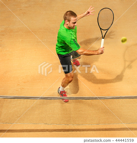 The one jumping player, caucasian fit man, playing tennis on the earthen court 44441559