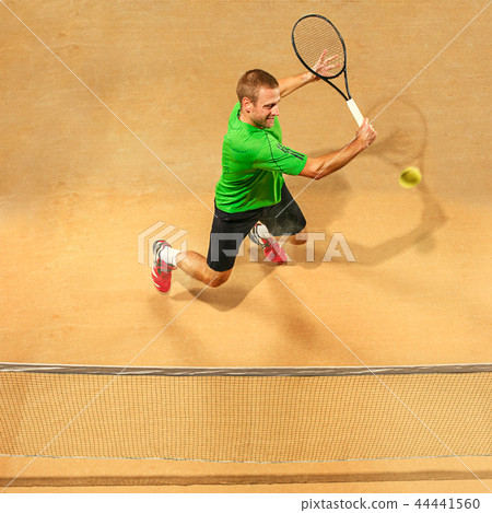 The one jumping player, caucasian fit man, playing tennis on the earthen court 44441560