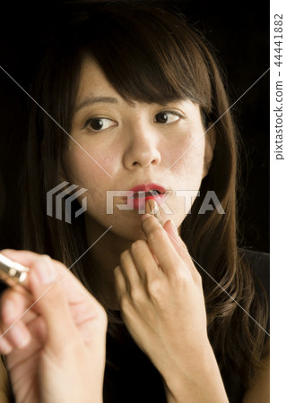 Woman doing makeup in the mirror Woman doing makeup in the mirror 44441882