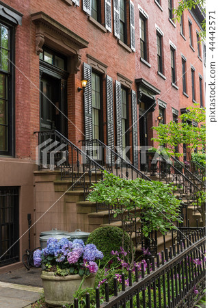 Row of old brownstone buildings along an empty sidewalk block in the Greenwich Village neighborhood Row of old brownstone buildings along an empty sidewalk block in the Greenwich Village neighborhood 44442571