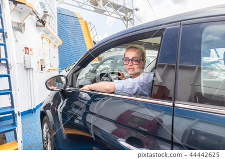 Female driver parking her car on ferry boat on trip to their summer vacations island destination Female driver parking her car on ferry boat on trip to their summer vacations island destination 44442625