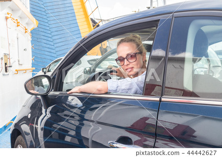 Female driver parking her car on ferry boat on trip to their summer vacations island destination Female driver parking her car on ferry boat on trip to their summer vacations island destination 44442627