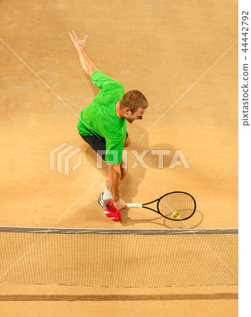 The one jumping player, caucasian fit man, playing tennis on the earthen court The one jumping player, caucasian fit man, playing tennis on the earthen court 44442792