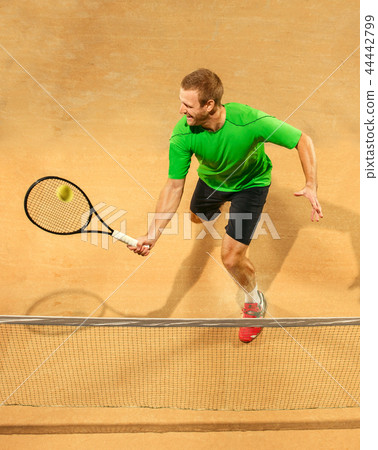The one jumping player, caucasian fit man, playing tennis on the earthen court The one jumping player, caucasian fit man, playing tennis on the earthen court 44442799