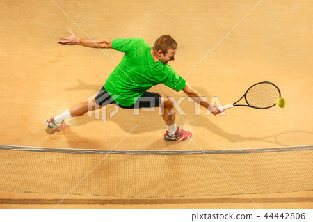The one jumping player, caucasian fit man, playing tennis on the earthen court 44442806