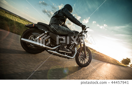 Man riding sportster motorcycle during sunset. 44457941