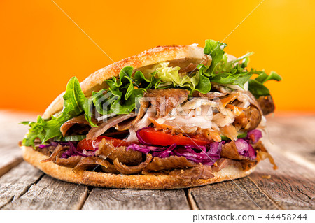 Close up of kebab sandwich on old wooden table. Close up of kebab sandwich on old wooden table. 44458244