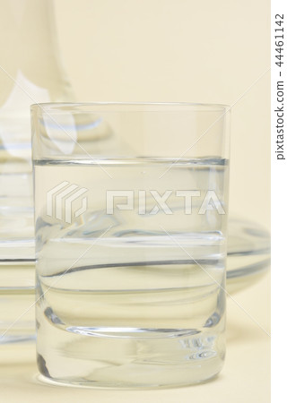 Glass and carafe with water on beige background 44461142