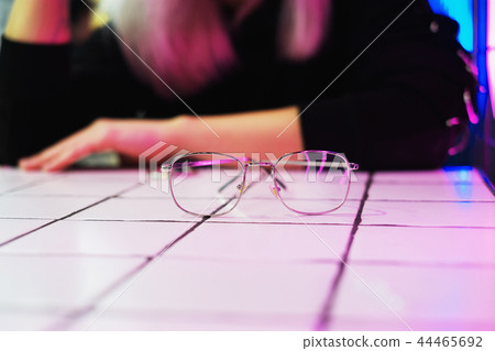 Glasses reflect neon light in cafe on background  44465692