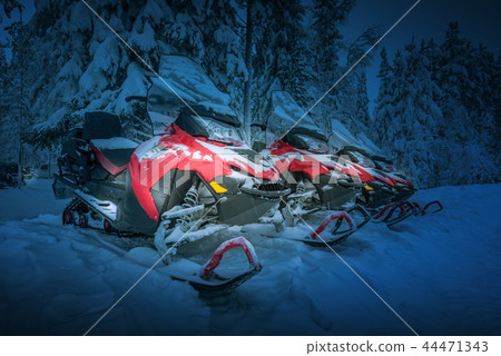 Polar night landscape with row of red snowmobiles 44471343