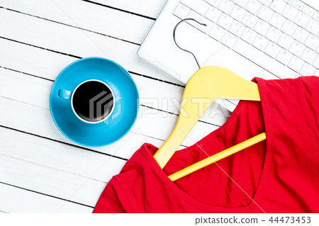 Cup of coffee and hanger with red dress near computer Cup of coffee and hanger with red dress near computer 44473453
