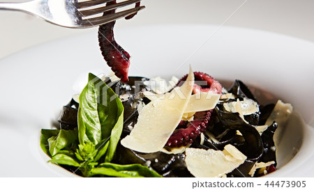 Pasta with black cuttlefish ink, octopuses and parmesan. Pasta with black cuttlefish ink, octopuses and parmesan. 44473905