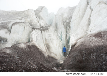 A free climber with an ice ax in his hand stands at the foot of the Great Glacier next to an epic A free climber with an ice ax in his hand stands at the foot of the Great Glacier next to an epic 44474486