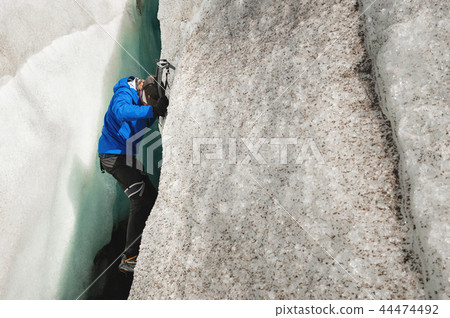 A free climber without insurance with two ice axes rises from a crack in the glacier. Free climbing 44474492