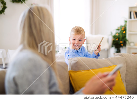 A mother and small boy with smartphones sitting on a sofa at home at Christmas time. A mother and small boy with smartphones sitting on a sofa at home at Christmas time. 44475240