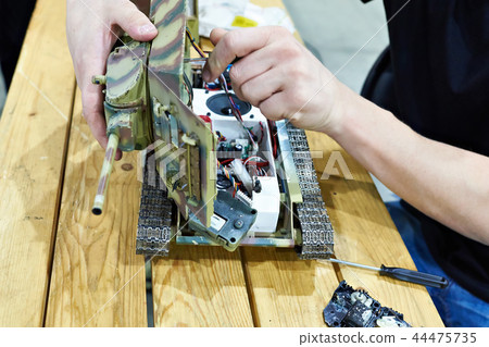 Man repairs a reduced model of soviet tank T-34 Man repairs a reduced model of soviet tank T-34 44475735