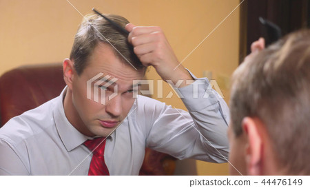 the concept of metrosexualism. a handsome man in front of a mirror takes care of his face. does the the concept of metrosexualism. a handsome man in front of a mirror takes care of his face. does the 44476149
