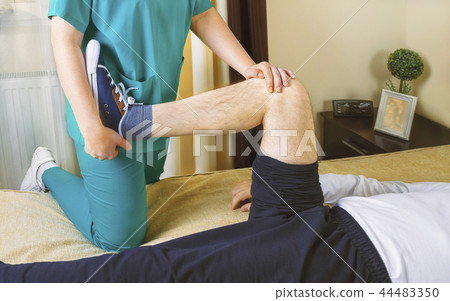Physiotherapist doing exercises for leg recovery  44483350