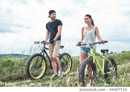 Young man looks at young beautiful woman with fatbike Young man looks at young beautiful woman with fatbike 44487519