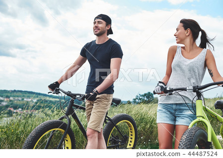 Young couple resting after bike ride in field 44487524