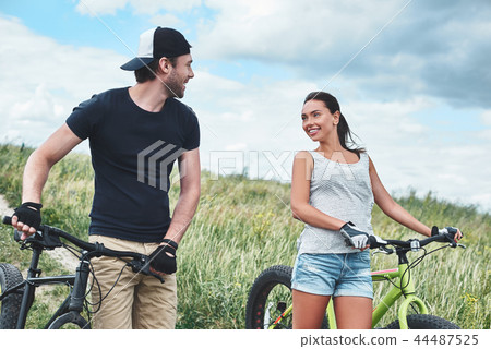 Young man looks at young beautiful woman with fatbike. Close up 44487525