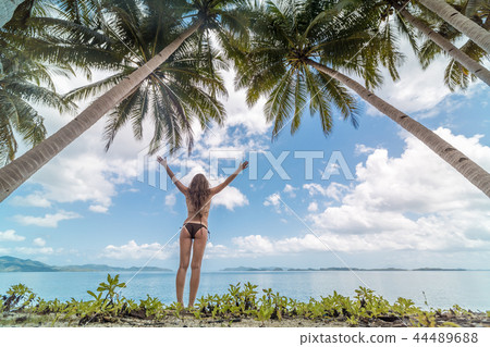 Beautiful young woman with arms open in a tropical beach enjoying the summer 44489688