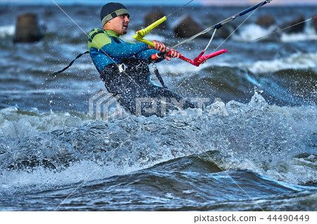 A male kiter slides on the surface of the water. A male kiter slides on the surface of the water. 44490449
