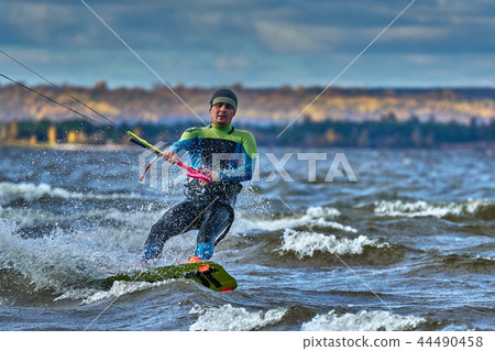 A male kiter slides on the surface of the water. A male kiter slides on the surface of the water. 44490458