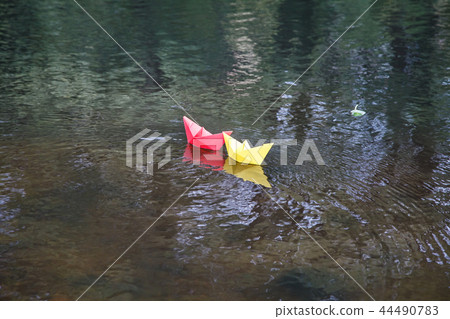 two multicolored paper boats floating on a stream 44490783