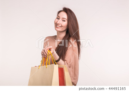 Fashion, shopping and people concept - happy brunette woman with paperbags after shopping 44491165