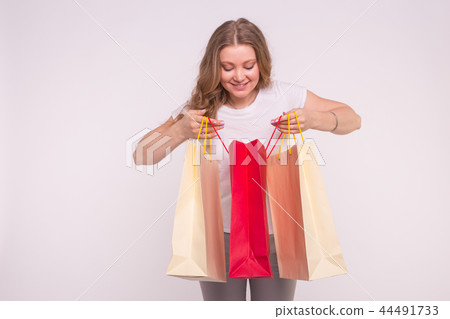 Young surprised blonde woman look into the shopping bag on white background 44491733