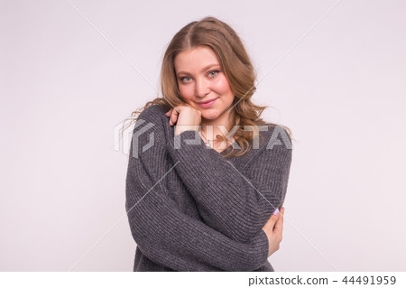 Young blonde woman wearing grey wool sweater on white background Young blonde woman wearing grey wool sweater on white background 44491959