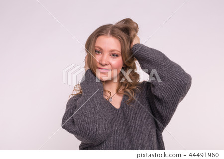 Portrait of fashionable young blonde woman with curly hair in grey cardigan on white background 44491960